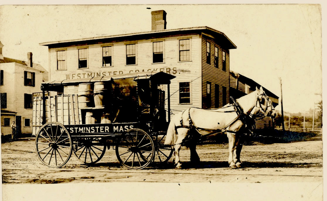Horse-drawn carriage with 'Westminster Mass' branding in front of a Westminster Crackers building.