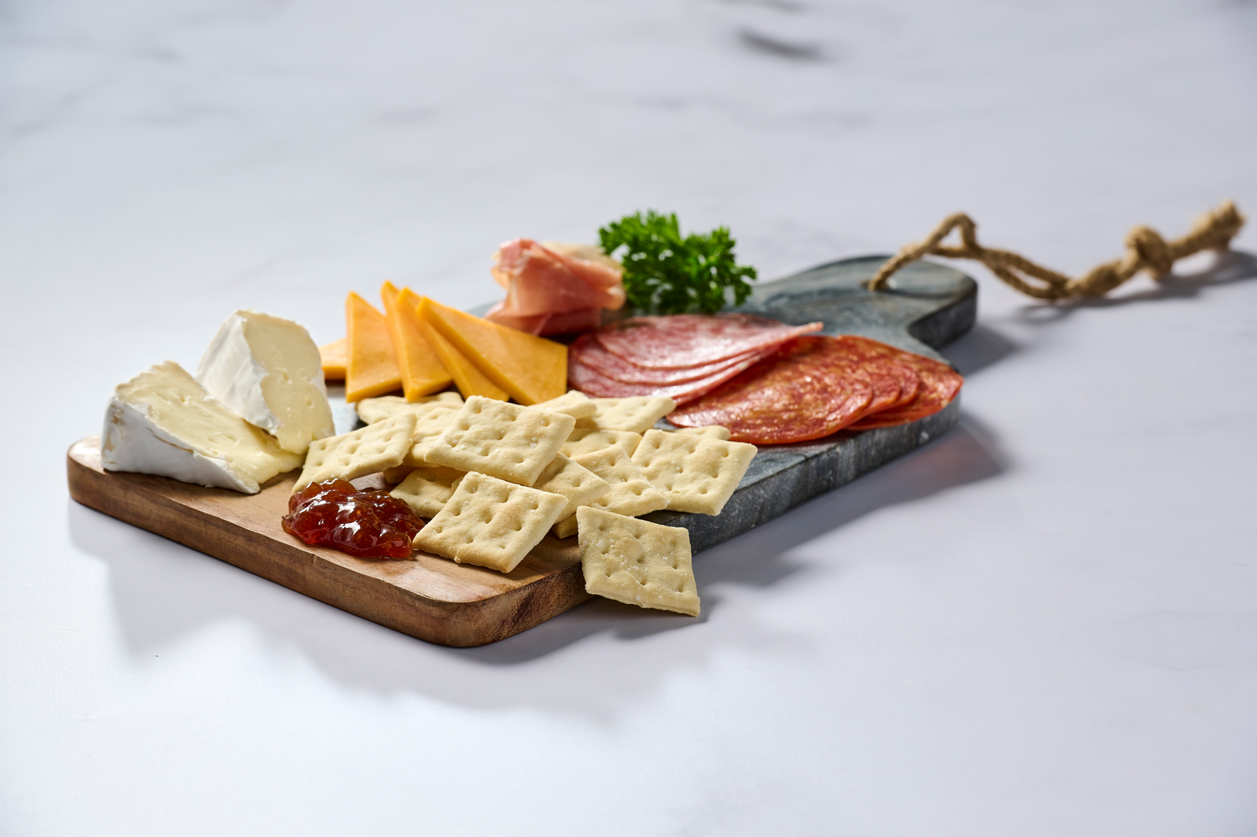 Charcuterie board with various meats, cheeses, and crackers on a marble surface