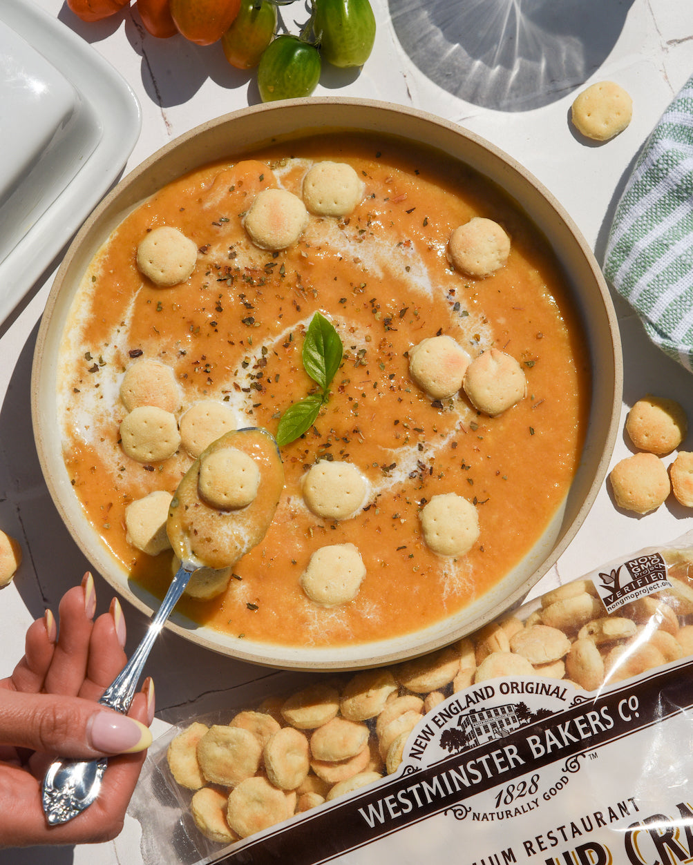  bowl of soup with crackers and a spoon, surrounded by Westminster Bakers Co. packaging